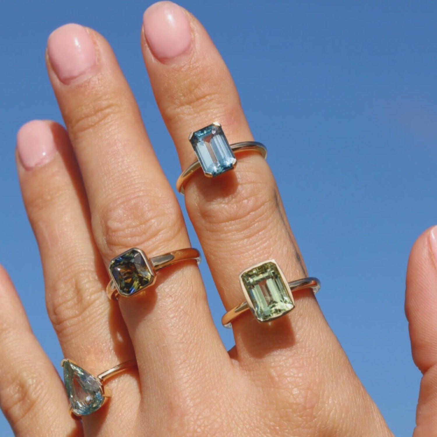 close up of hand with multiple to the sea collection rings stacked on fingers