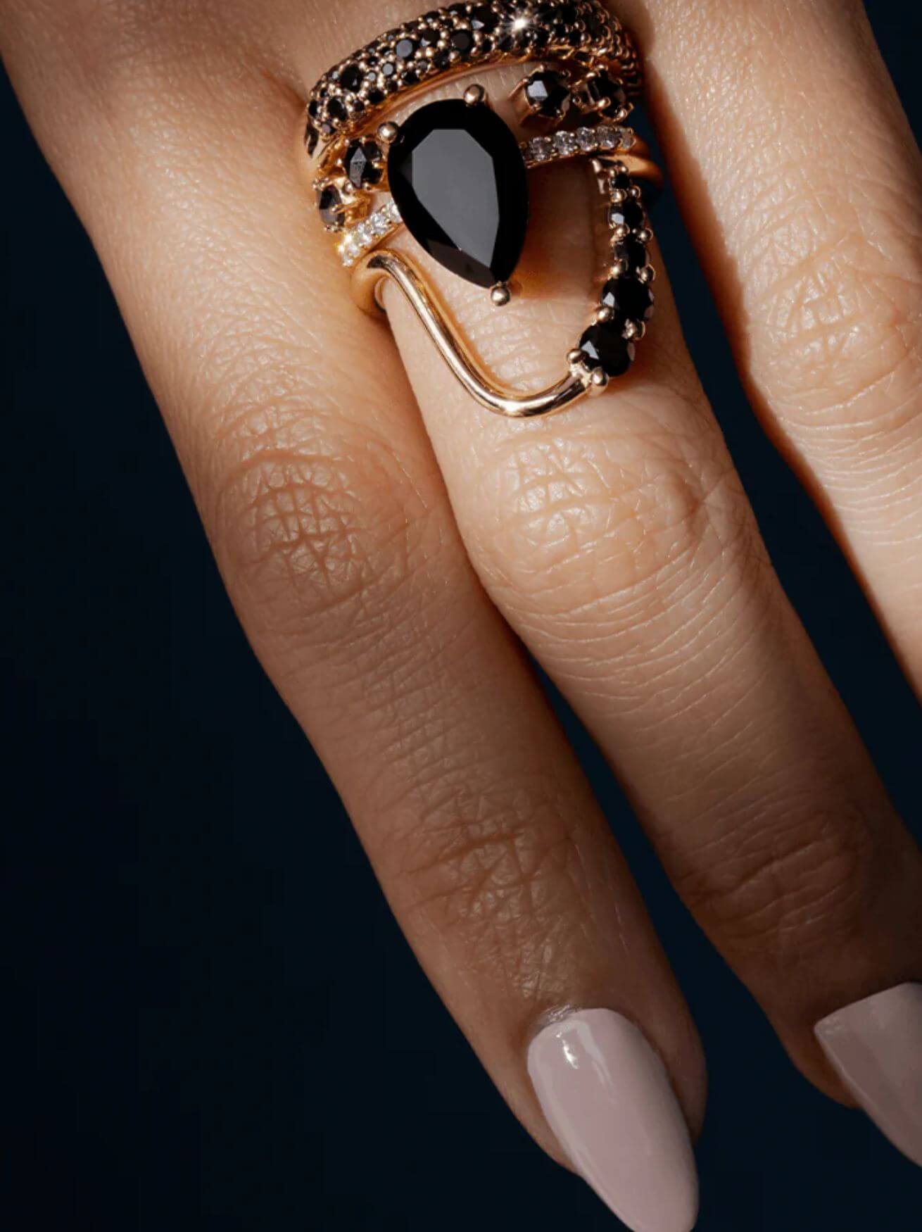 Close up of woman's hand with a ring stack featuring Marrow's Sweet Melissa Black Onyx Ring and Black Diamond bands.
