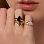 Close up of woman resting hand against her chin, highlighting multiple Marrow Fine rings styled and stacked together
