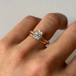 Image of Marrow Fine Everyday Petite Band stacked with a white diamond oval solitaire ring on a hand.