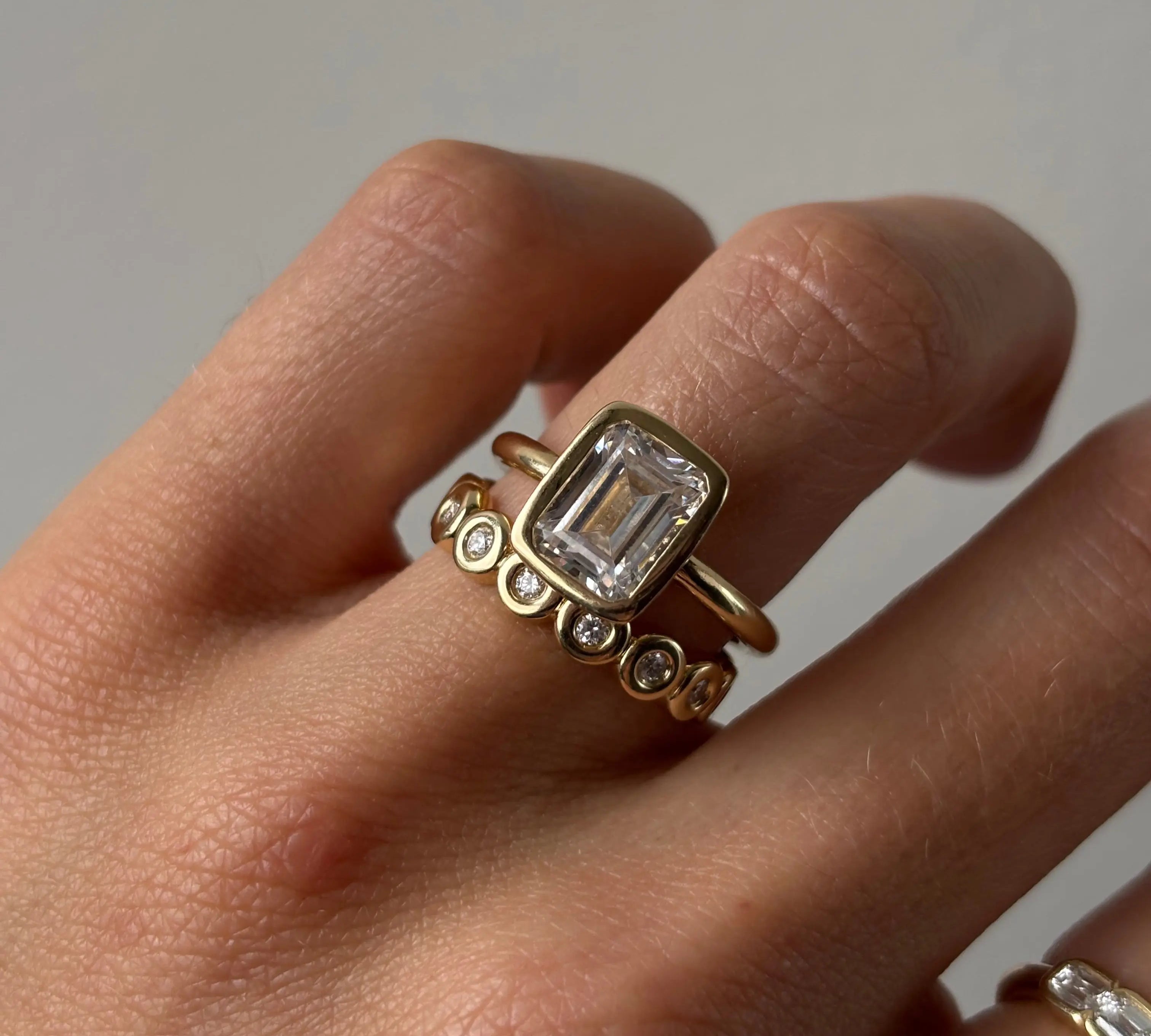 The Roxy Bezeled Emerald Cut Engagement Ring on hand
