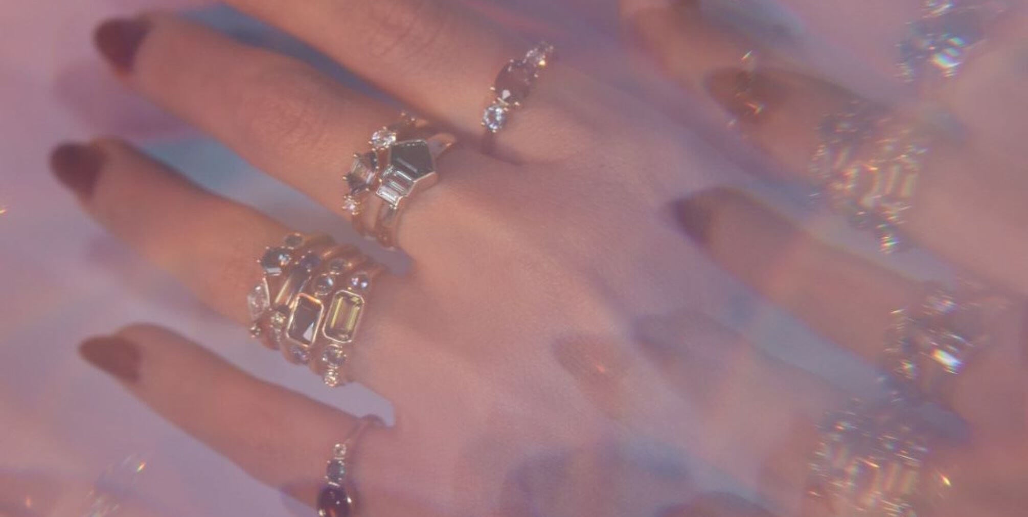 Close up of hand with multiple rings stacked from the Kaleidoscope Collection, with a kaleidoscope filter