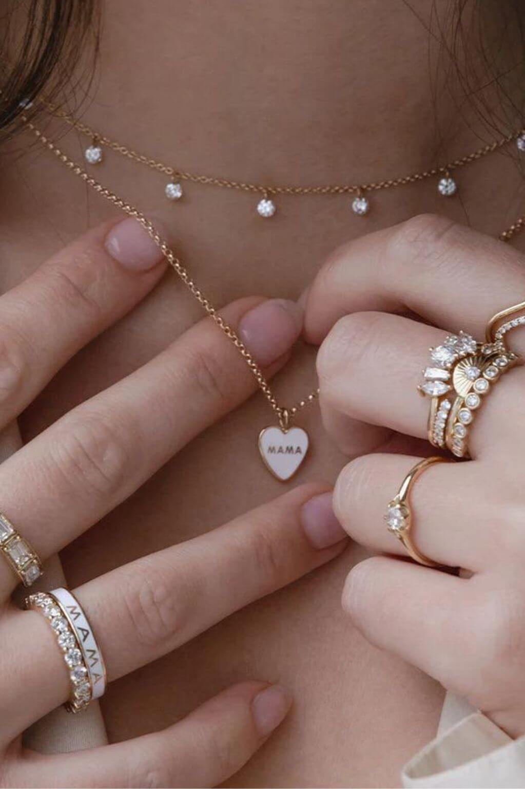 close up of woman's neckline with hands reaching for necklace, featuring Marrow Fine necklaces and rings