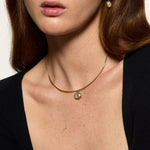 Close-up of a woman wearing a gold necklace with a pendant.