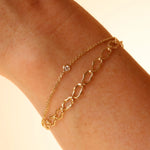 Gold chain bracelet on a wrist against a beige background