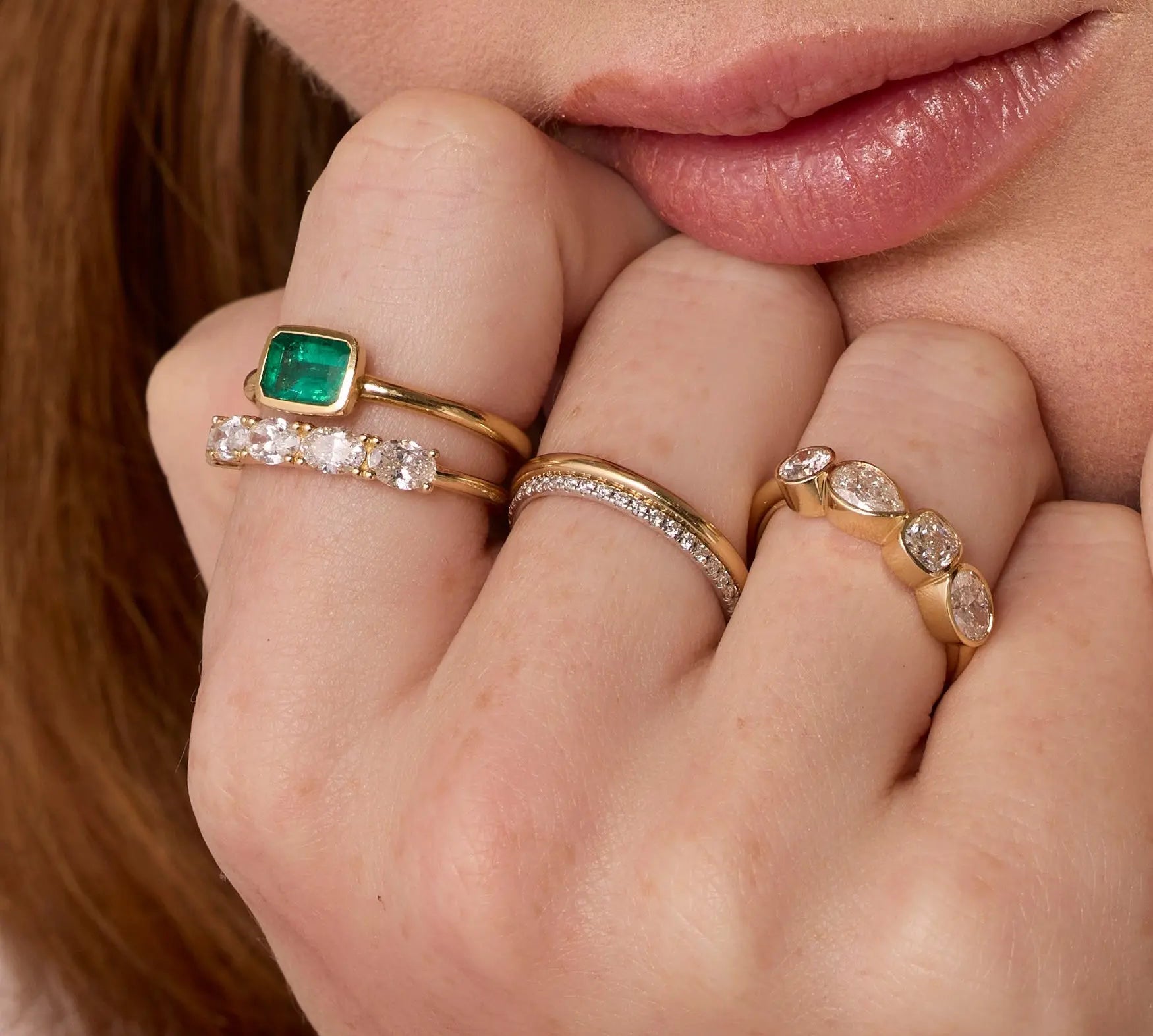 Close up of hand resting against woman's chin featuring multiple styled Marrow Fine rings