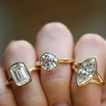 Close up of The Roxy Bezeled Emerald Cut Engagement Ring + The Tessa Bezel Round Solitaire Engagement Ring + The Colette Marquise Split Shank Engagement Ring