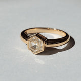 Image of a Marrow Fine one of a kind diamond solitaire ring. The center white diamond is a hexagon cut and bezel set in 14k yellow gold.