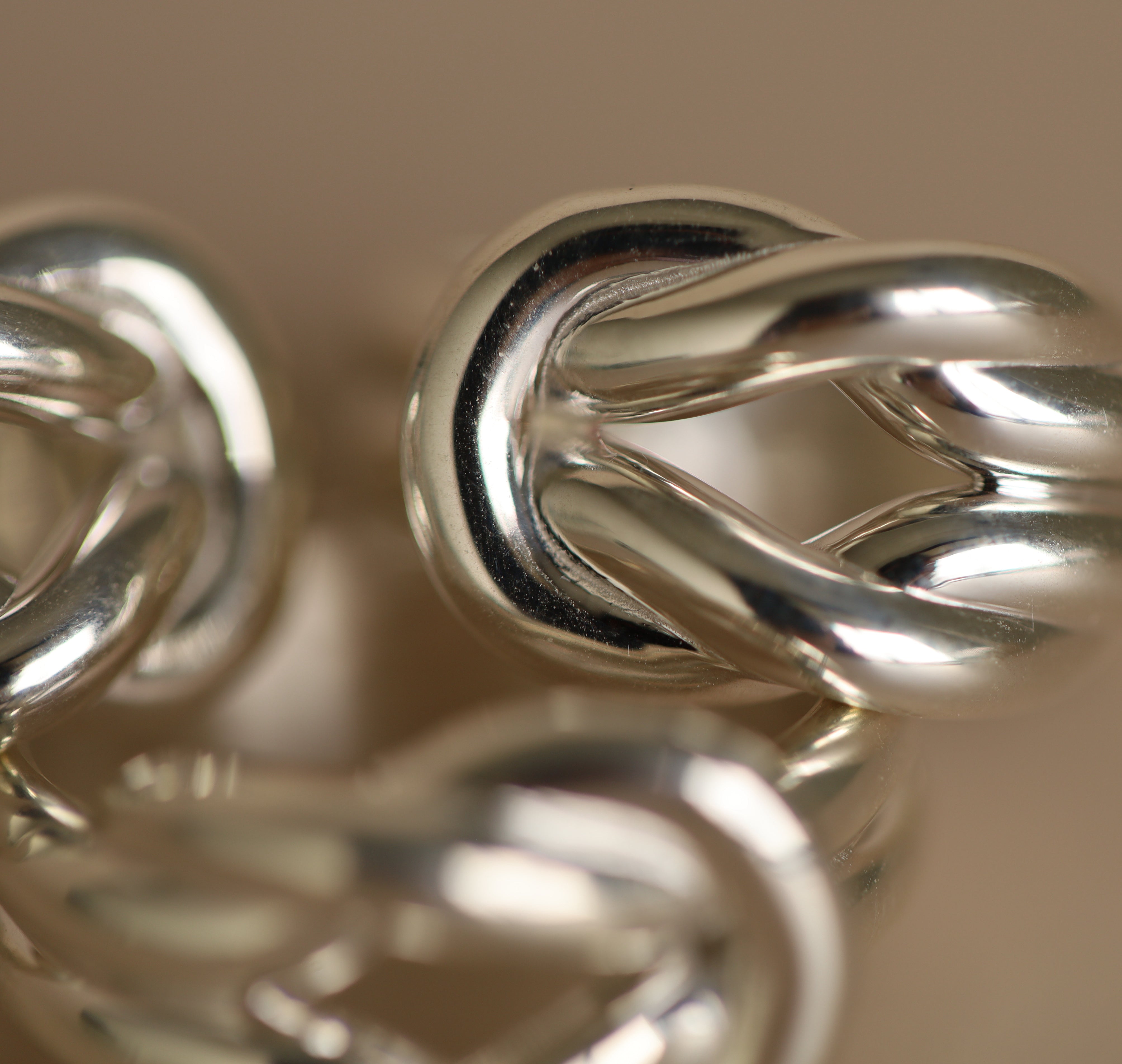Close-up of silver jewelry with intricate design on a beige background