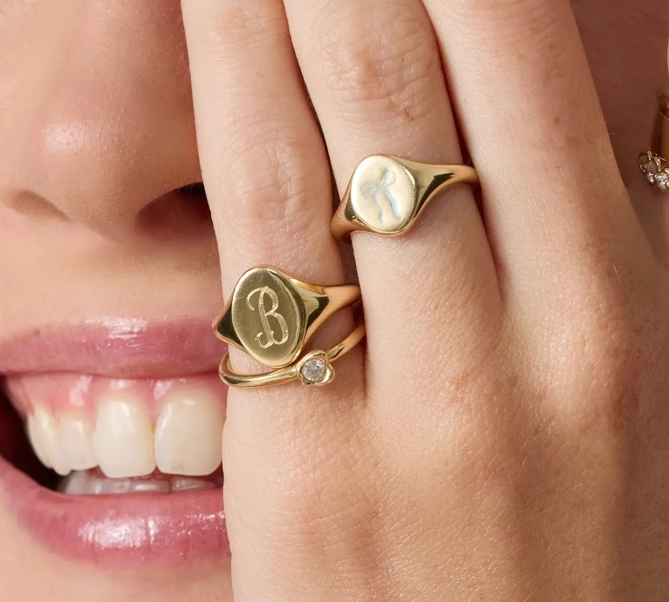 Close-up of a person wearing gold rings with initials on their fingers.