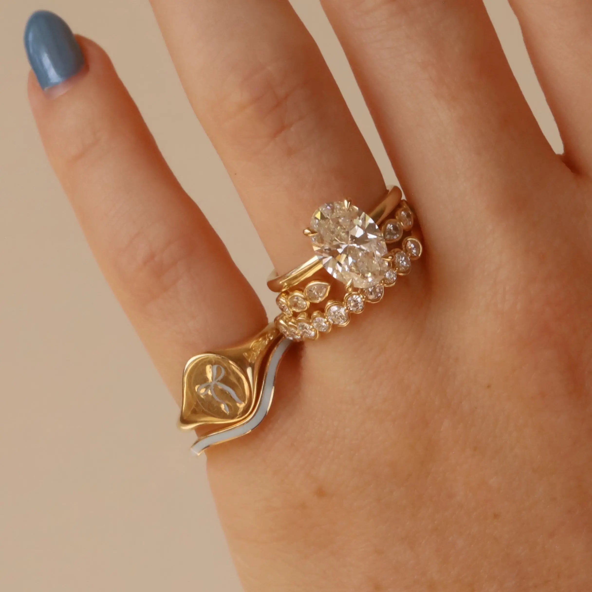 Gold and silver ring with a large diamond on a hand against a beige background