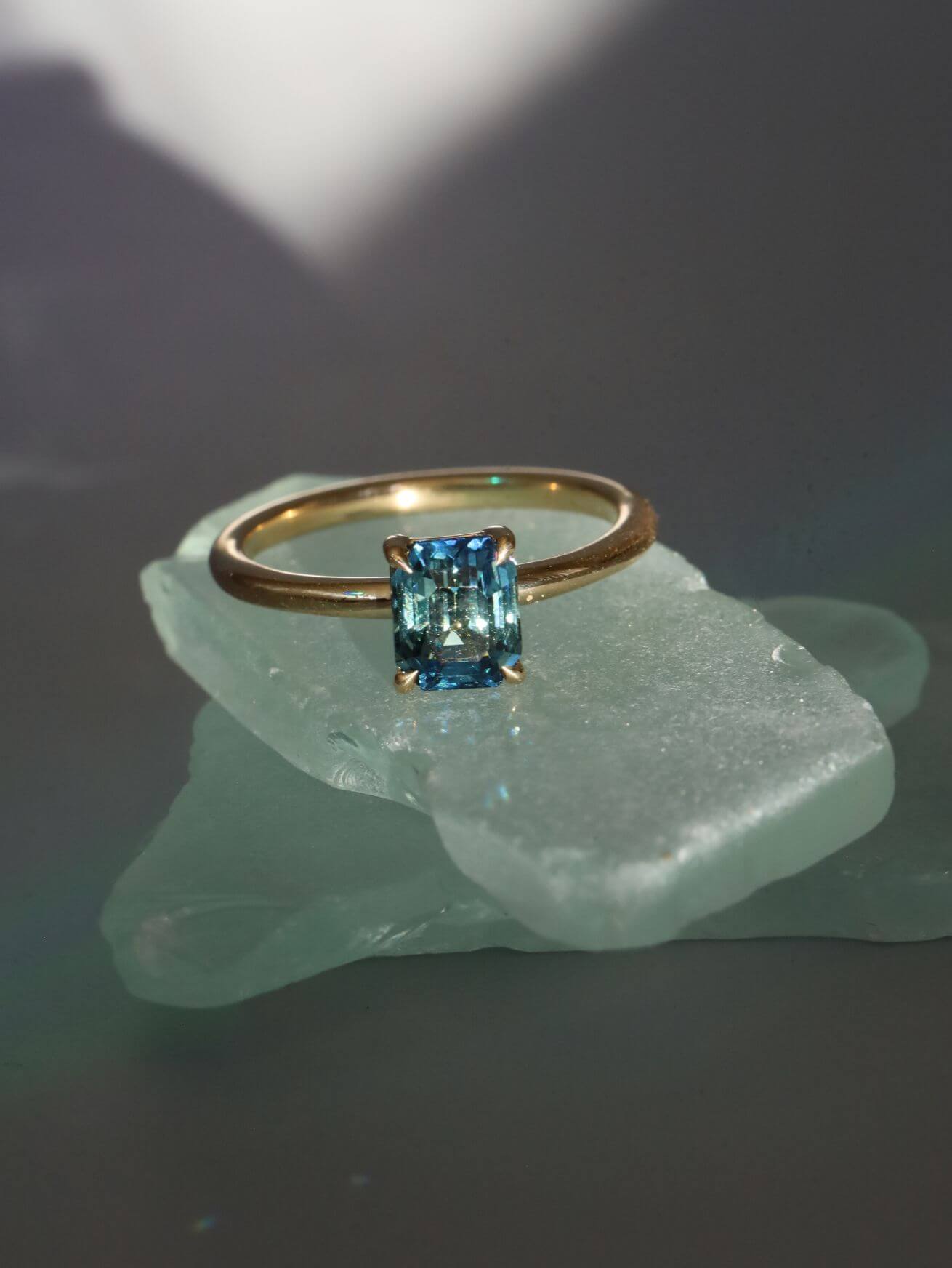 frontal shot of a sapphire solitaire ring from our to the sea collection, styled on top of some sea glass