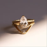 Gold ring with a pear-shaped diamond on a gradient background