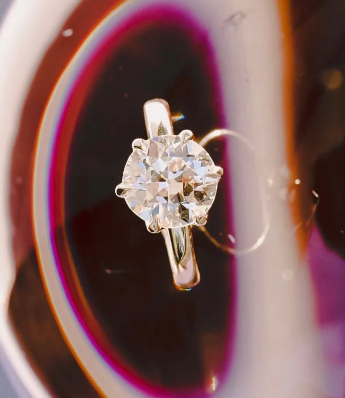 Birds Eye shot of an old European cut white diamond solitaire ring against an abstract background