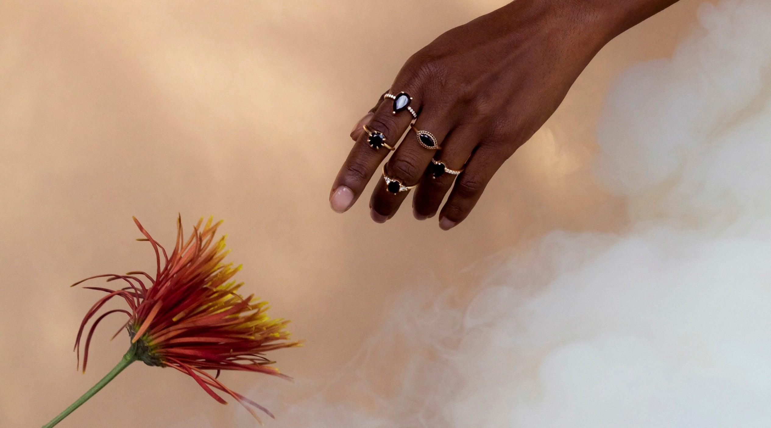 Woman's hand with Marrow rings reaching for flower