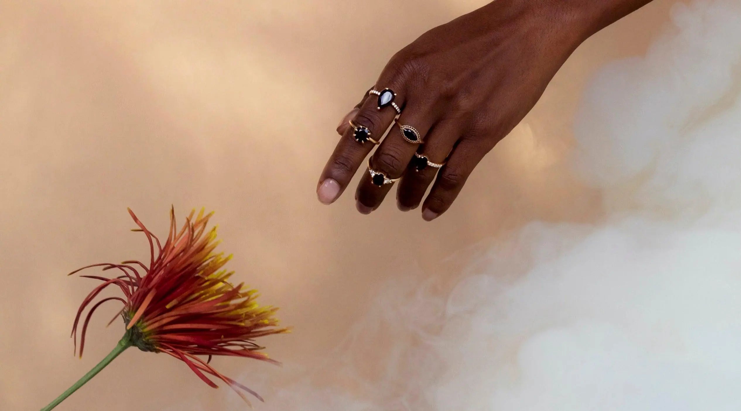 Woman's hand with Marrow rings reaching for flower