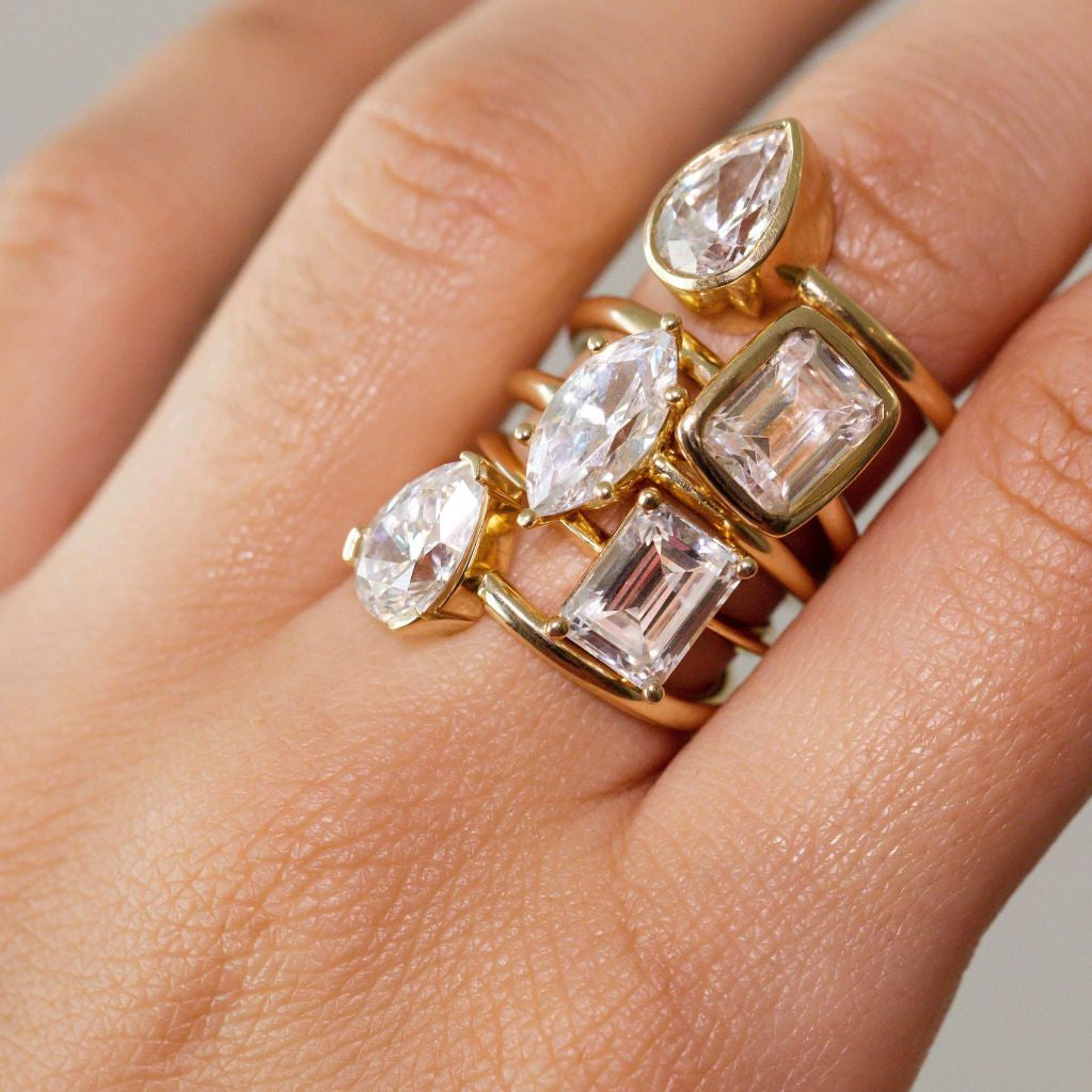 Close up of woman's hand with multiple white diamond rings stacked on the same finger.
