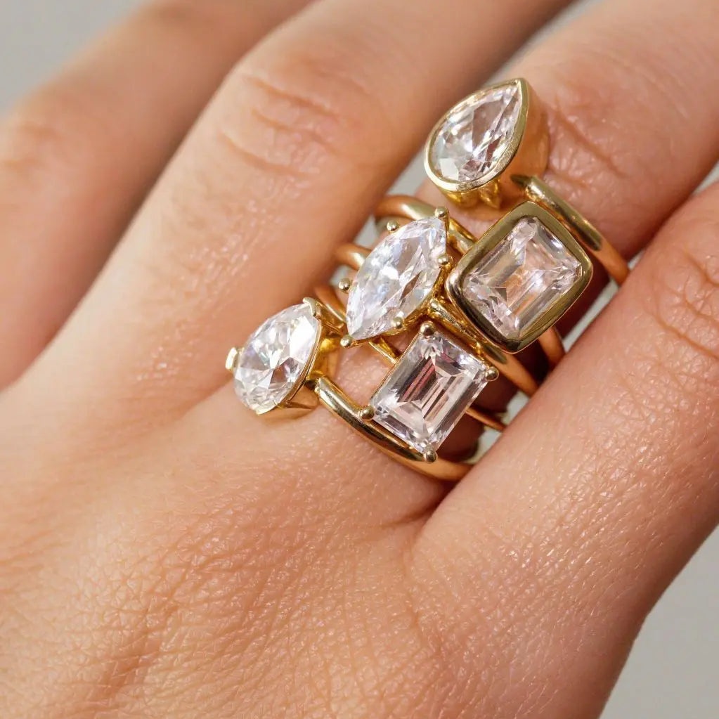 Close up of woman's hand with multiple white diamond rings stacked on the same finger.