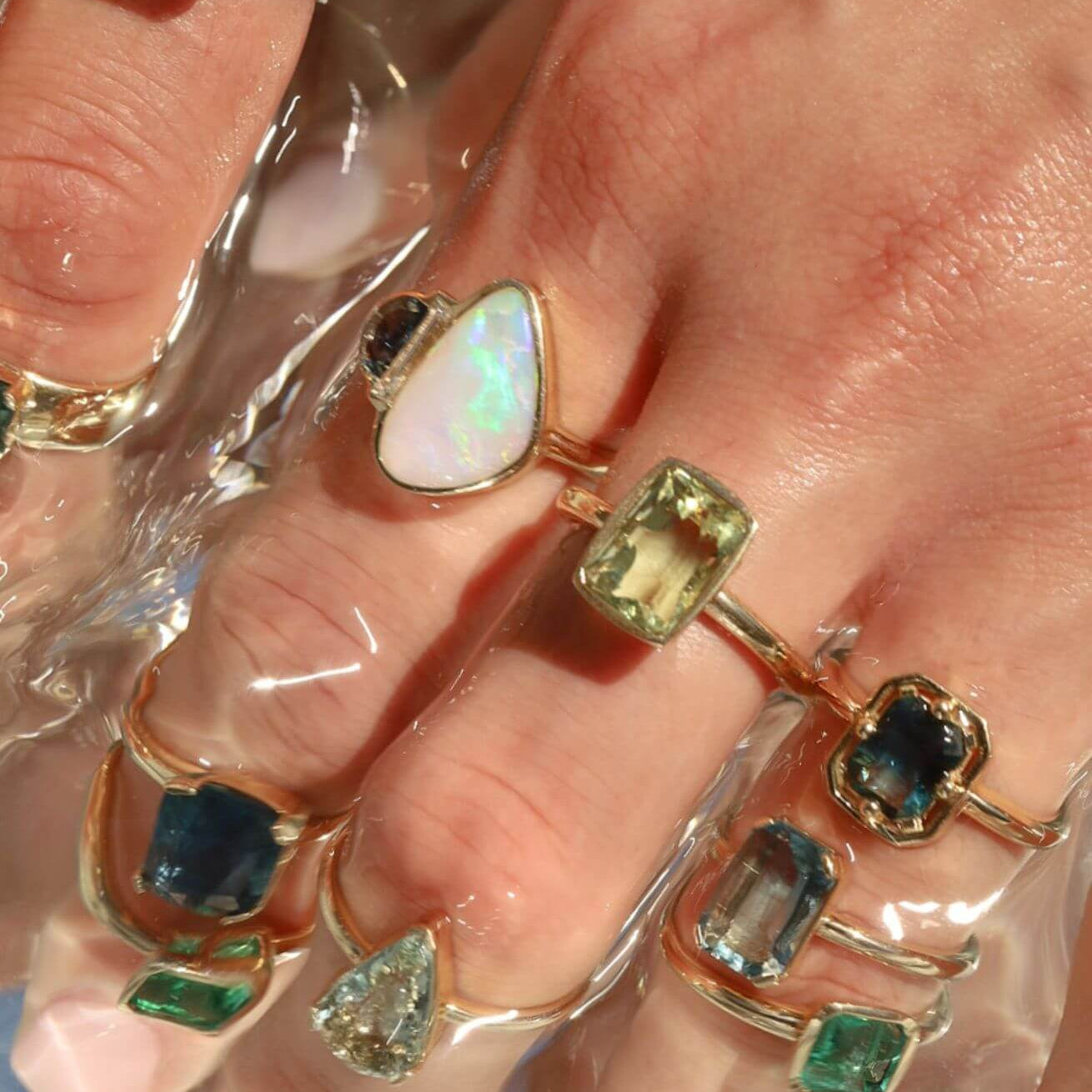 close up of a woman's hand with multiple to the sea collection rings stacked on fingers