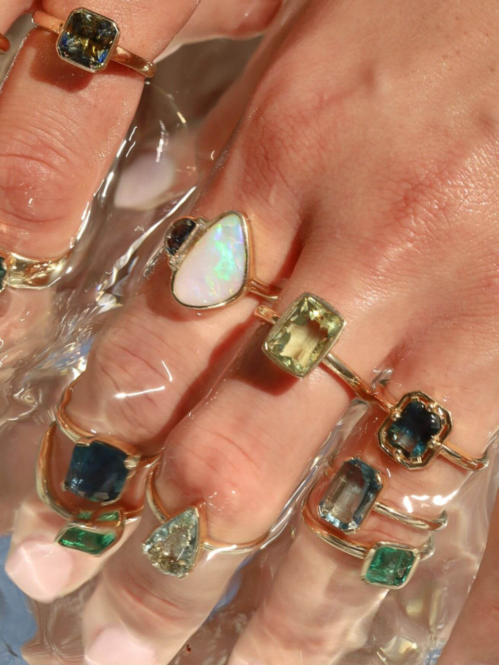 close up of a woman's hand with multiple to the sea collection rings stacked on fingers
