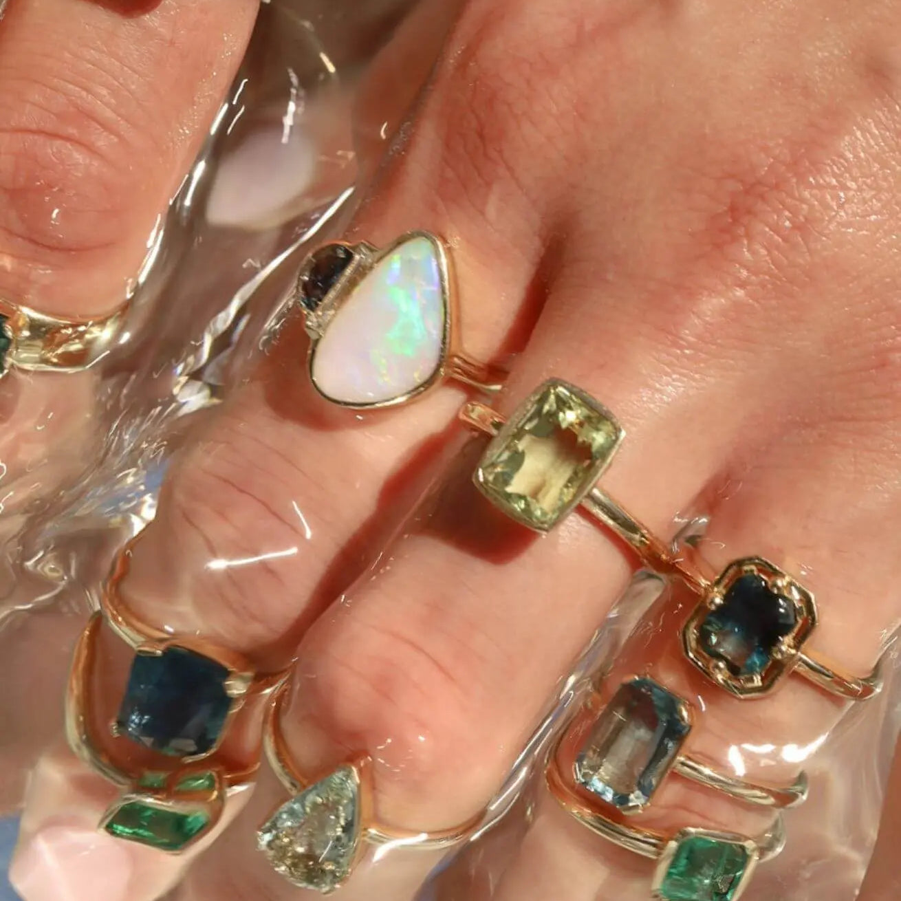 close up of a woman's hand with multiple to the sea collection rings stacked on fingers
