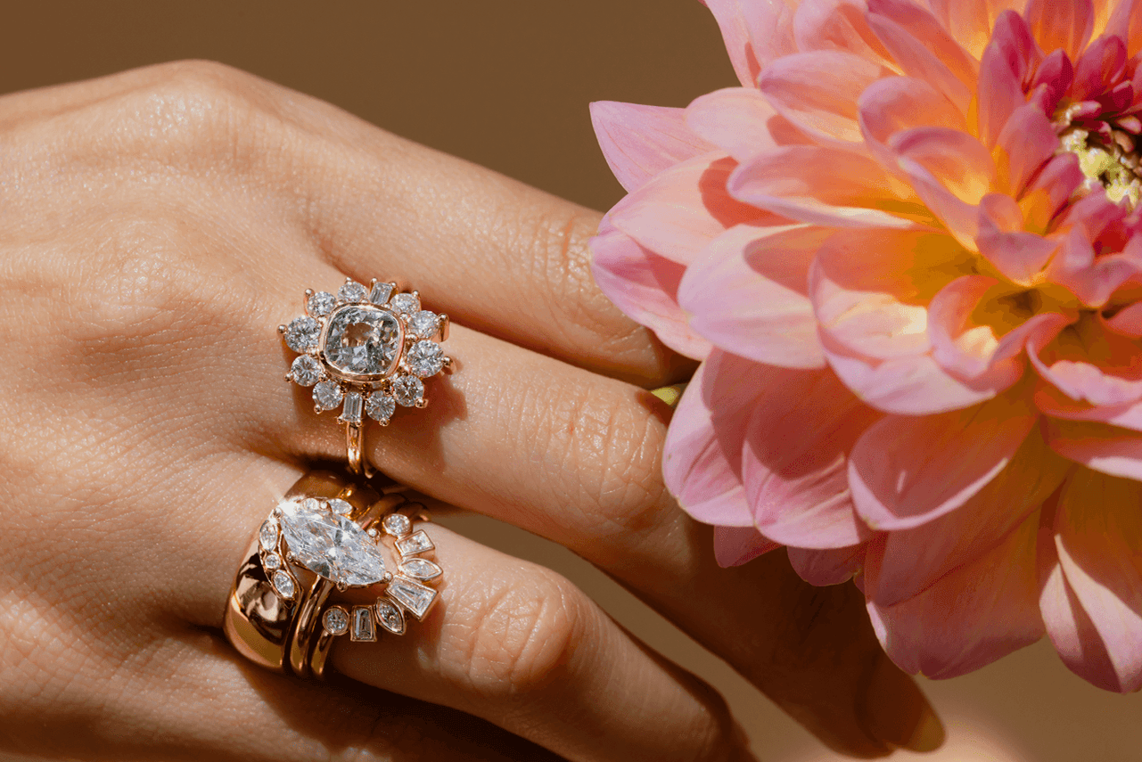 close up of woman's hand with Marrow rings grabbing for a pink flower