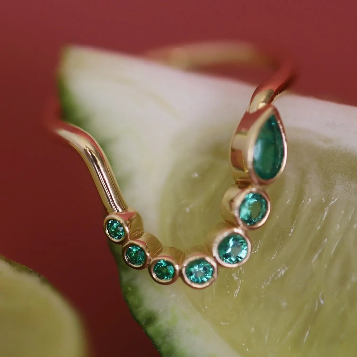 Gold earring with green gemstones on a slice of lime