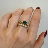 Gold ring with a green gemstone on a hand against a plain background