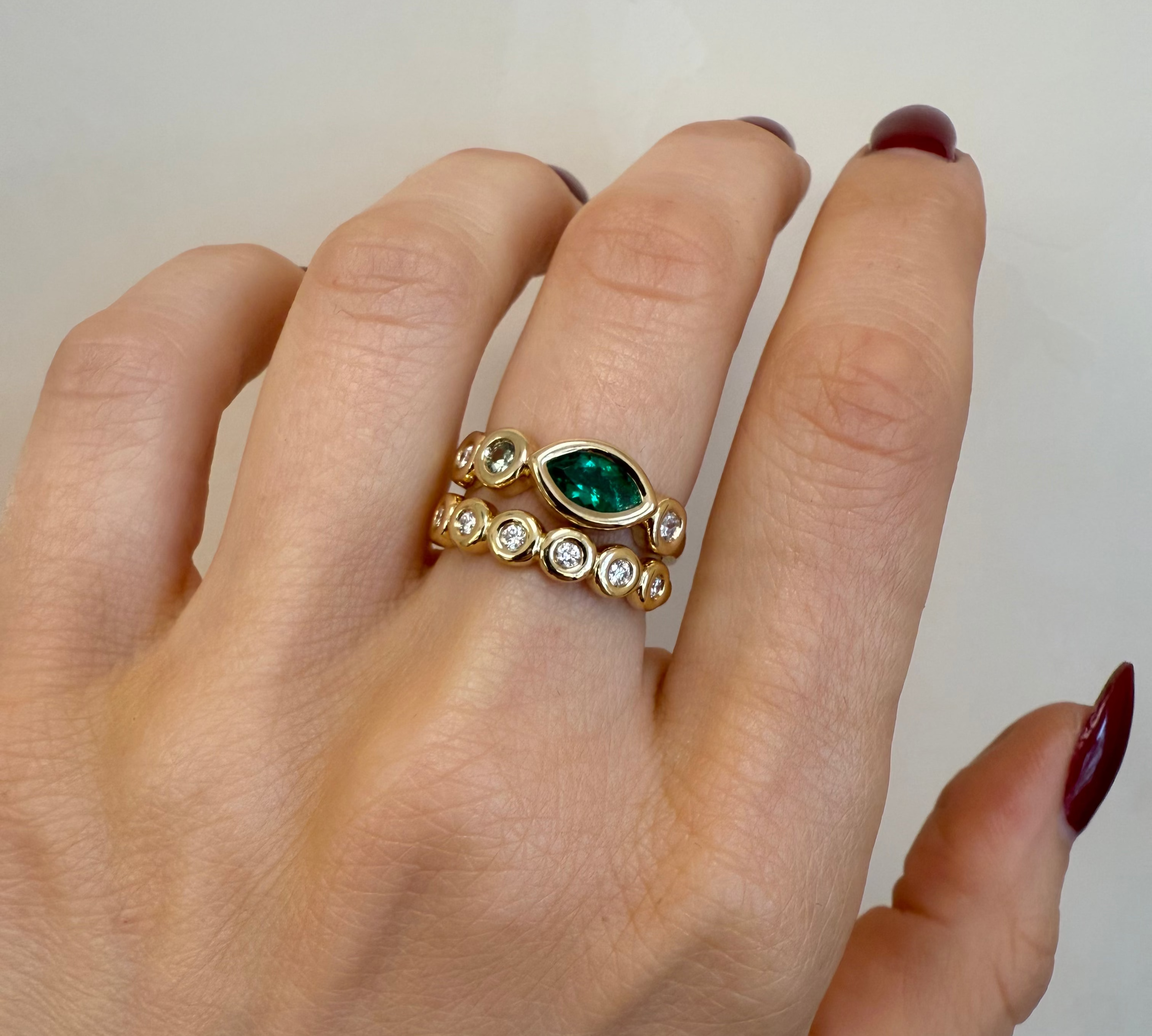 Gold ring with a green gemstone on a hand against a plain background