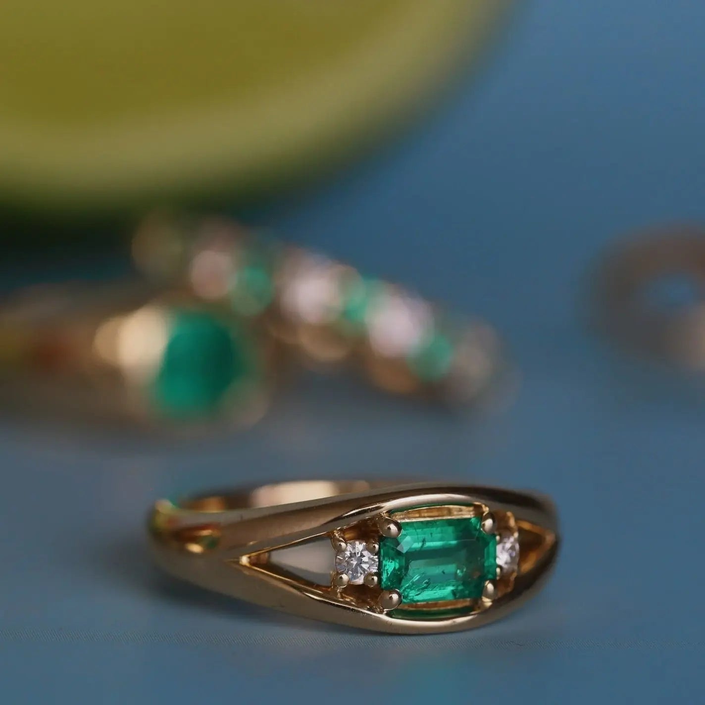 Gold ring with emerald and diamond on a blue background