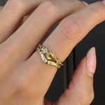 Gold ring with a diamond on a person's finger against a black background