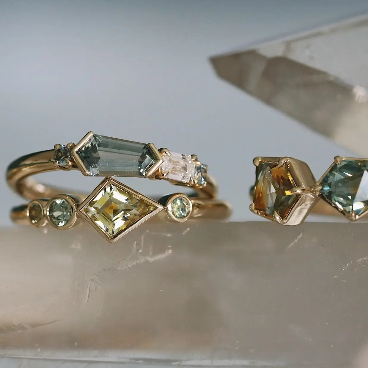 Three gold rings with gemstones on a reflective surface