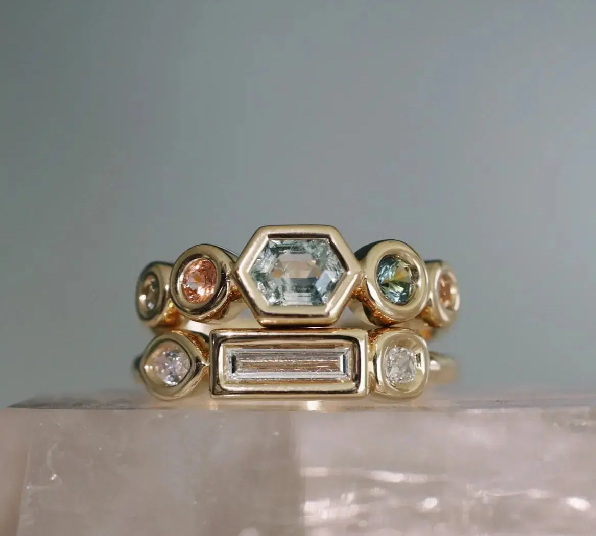 Gold ring with various gemstones on a gray background