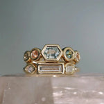 Gold ring with various gemstones on a gray background