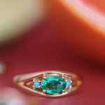 Gold ring with a green gemstone on a red background