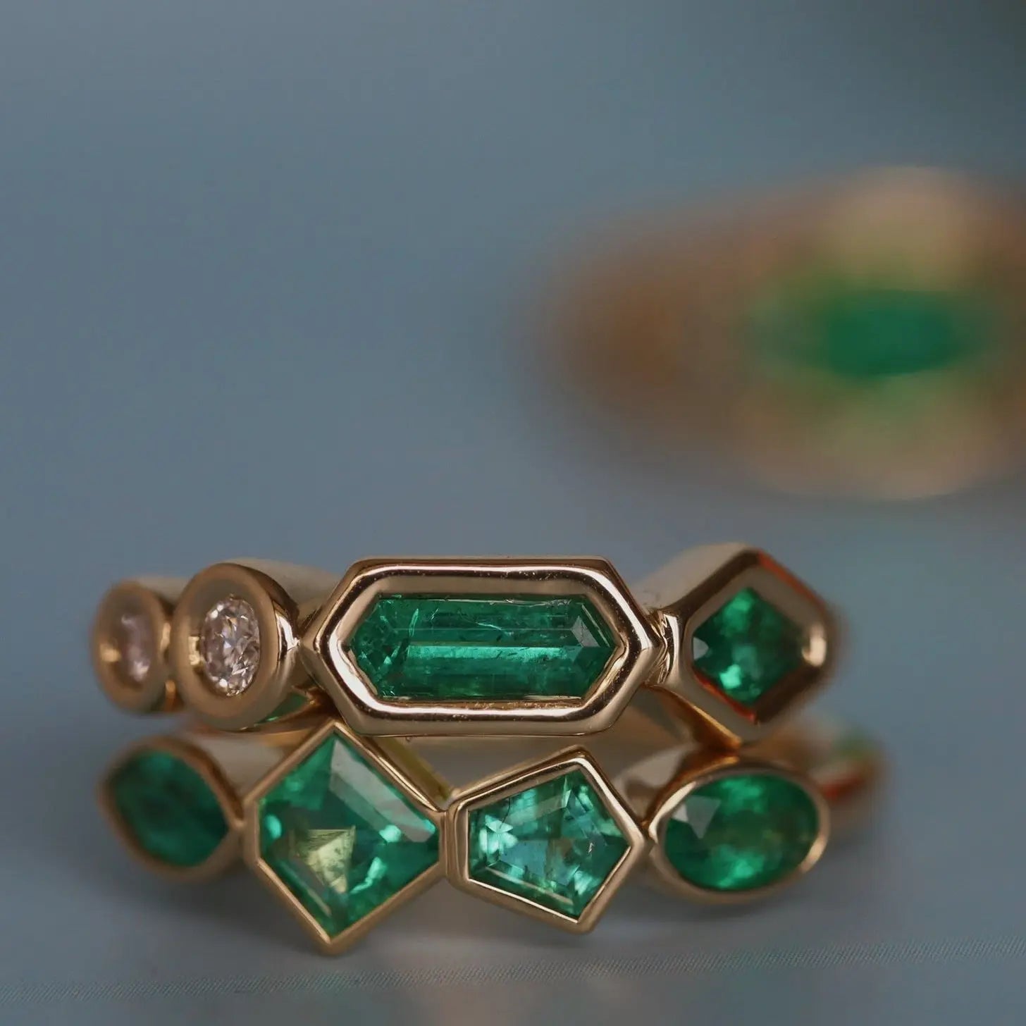 Gold ring with emeralds and diamonds on a blue background