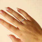 Hand wearing a white gold ring with a diamond on a beige background
