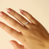Hand wearing a white gold ring with a diamond on a beige background
