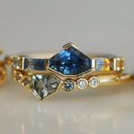 Gold ring with blue gemstone and smaller diamonds on a light background