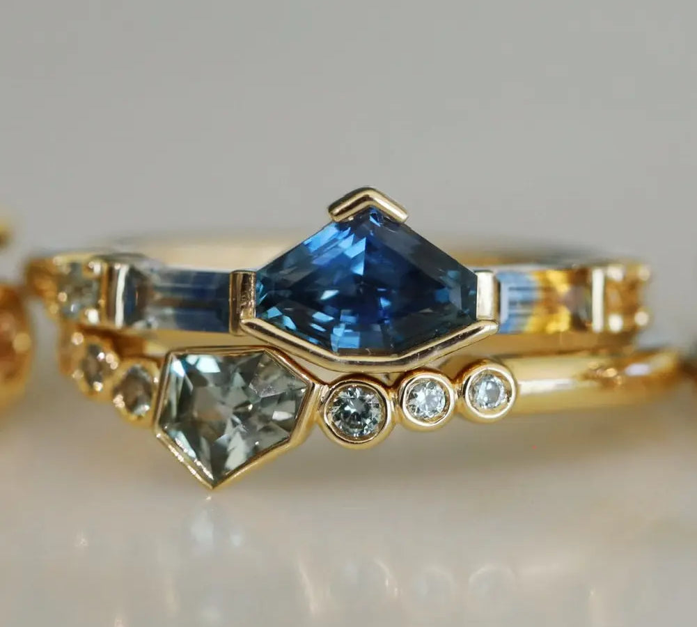 Gold ring with blue gemstone and smaller diamonds on a light background