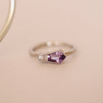 Silver ring with a purple gemstone on a beige background