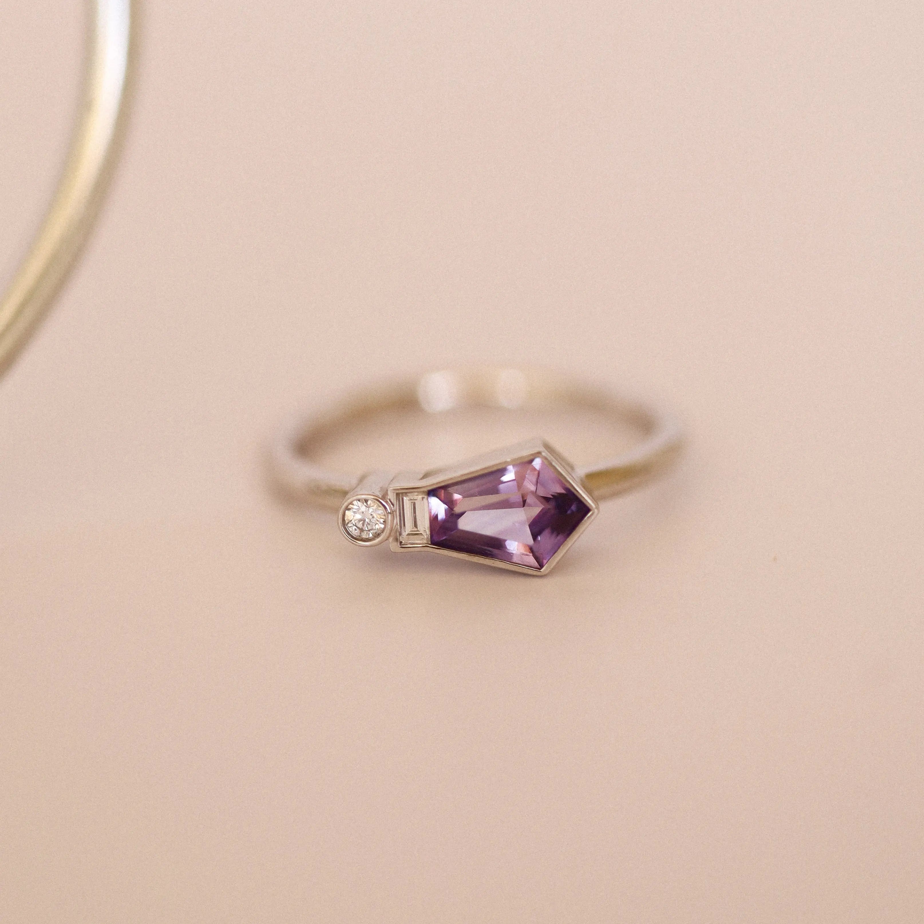 Silver ring with a purple gemstone on a beige background