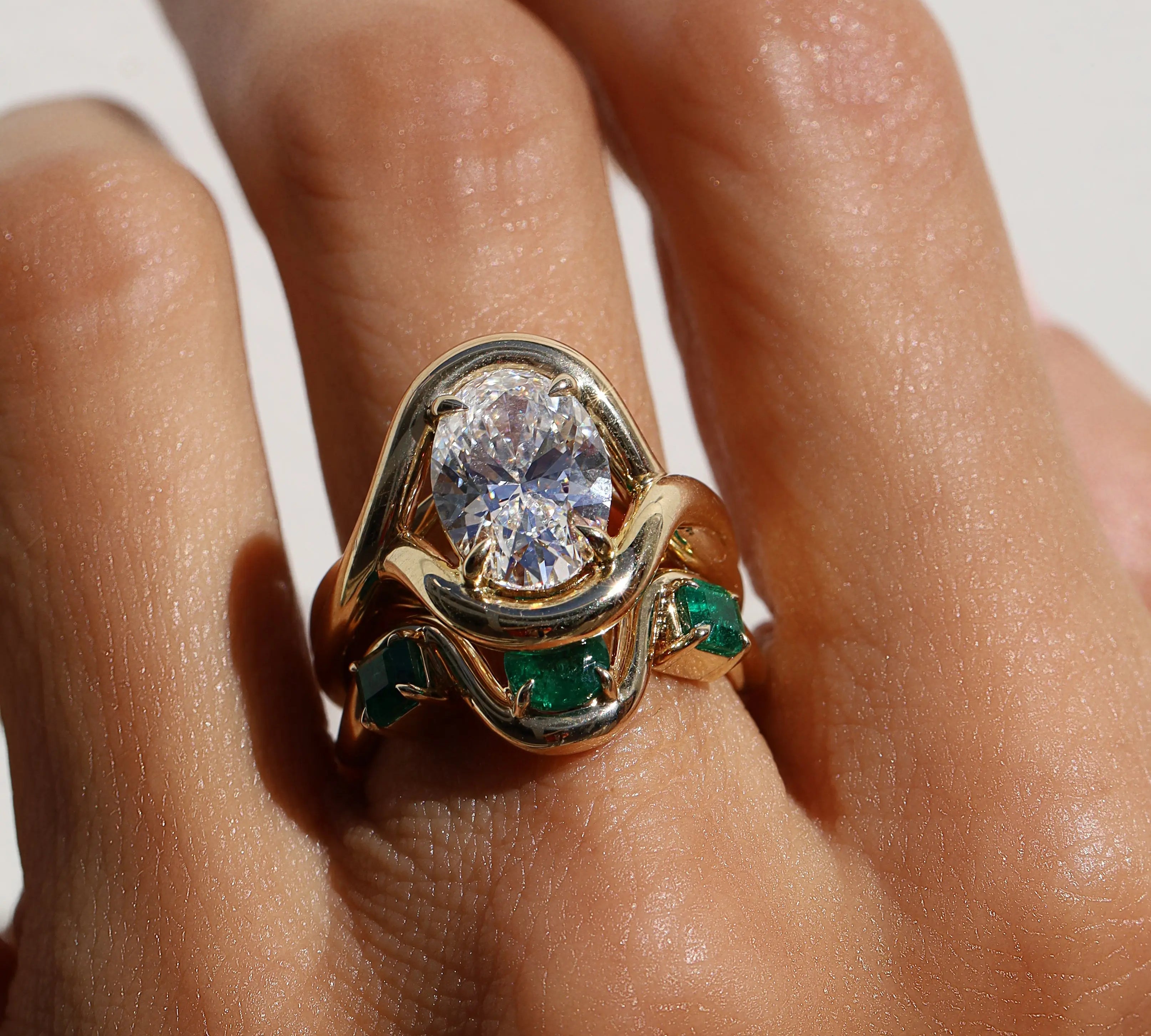 diamond ring with emerald tracer band on hand against a white background