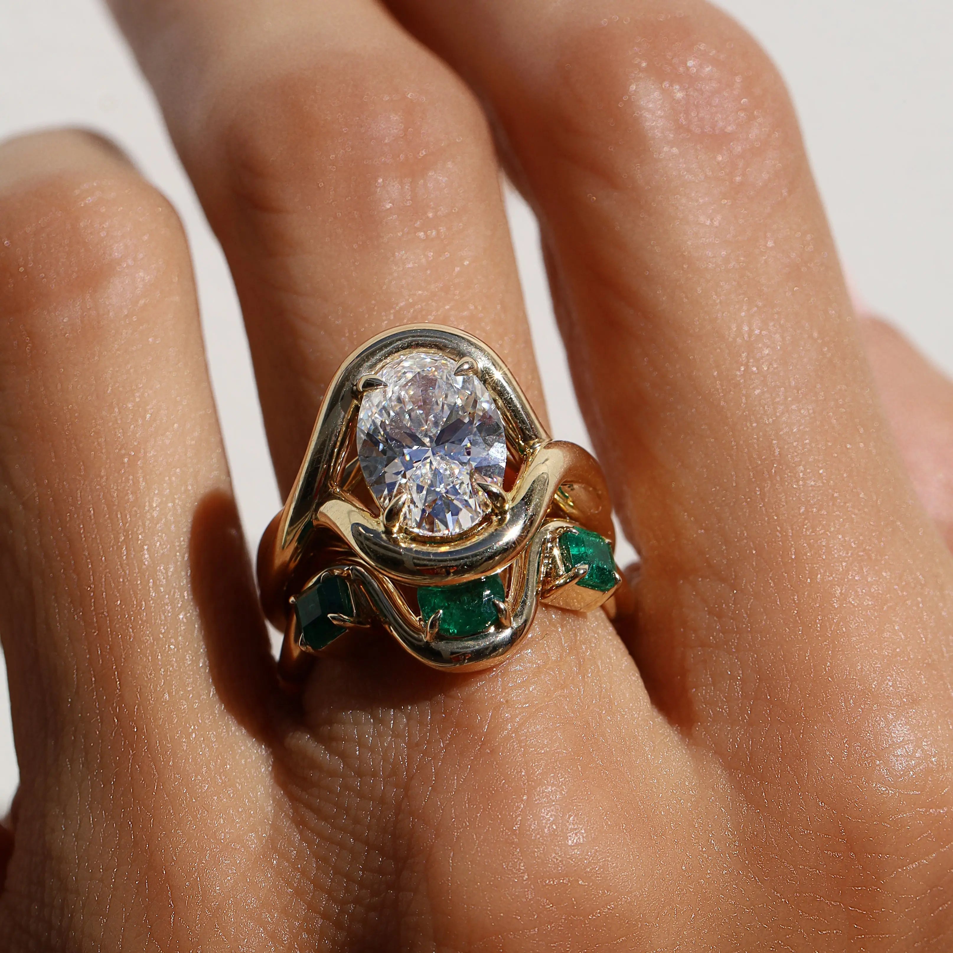 diamond ring with emerald tracer band on hand against a white background