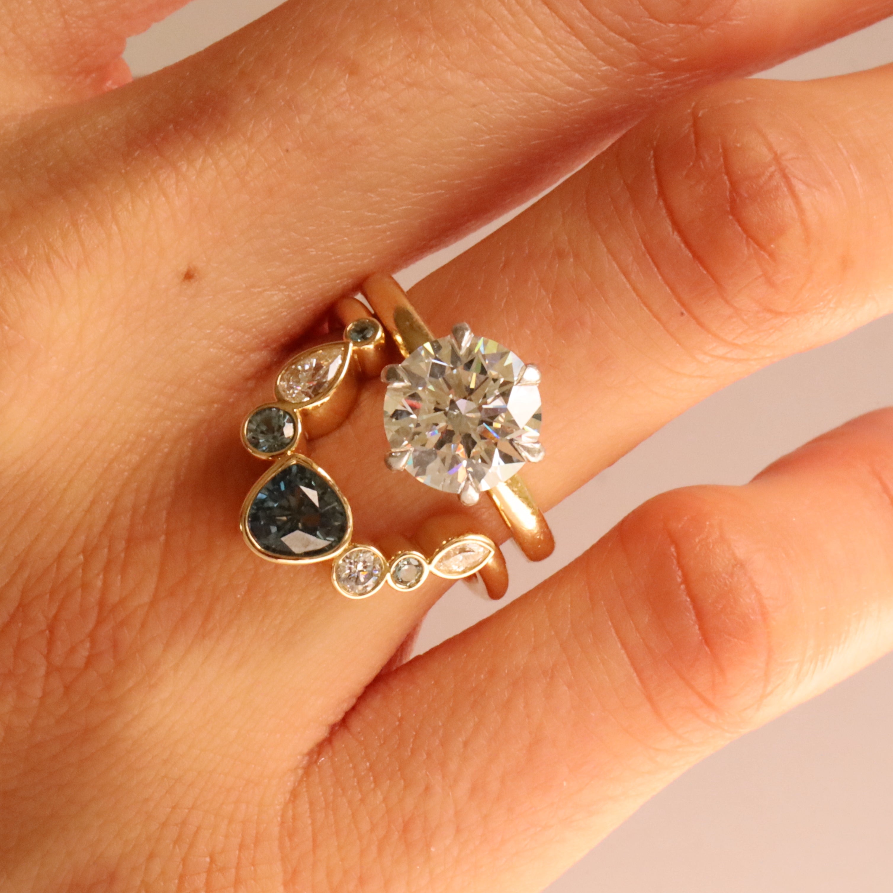 Close up of 1.05ct Sapphire and Diamond Kaleidoscope Chevron Ring stacked on woman's hand