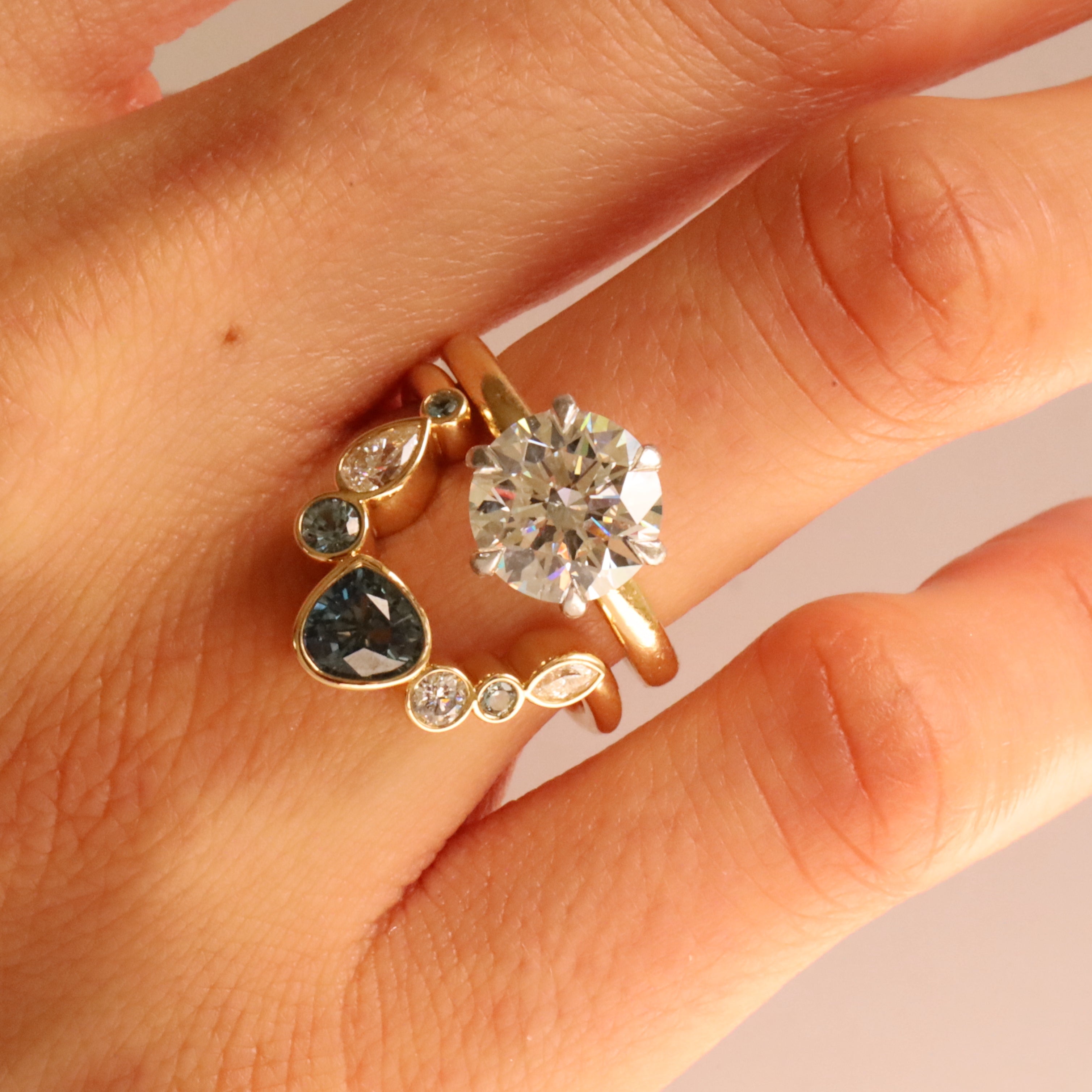 Close up of 1.05ct Sapphire and Diamond Kaleidoscope Chevron Ring stacked on woman's hand