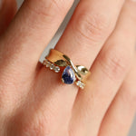 Gold ring with a blue gemstone on a person's finger