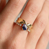 Gold ring with a blue gemstone on a person's finger