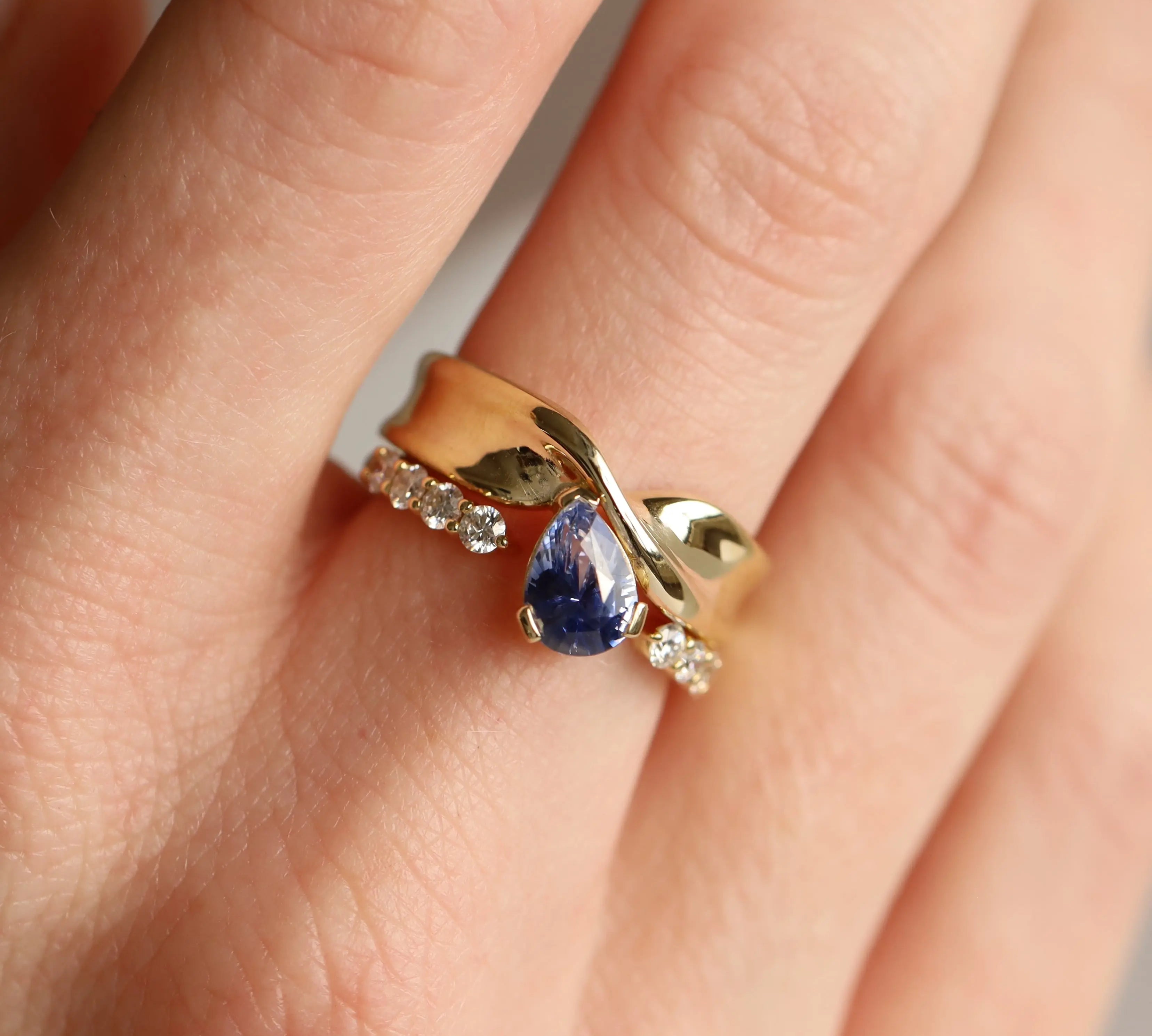Gold ring with a blue gemstone on a person's finger