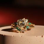 Gold ring with emerald and diamond stones on a textured surface